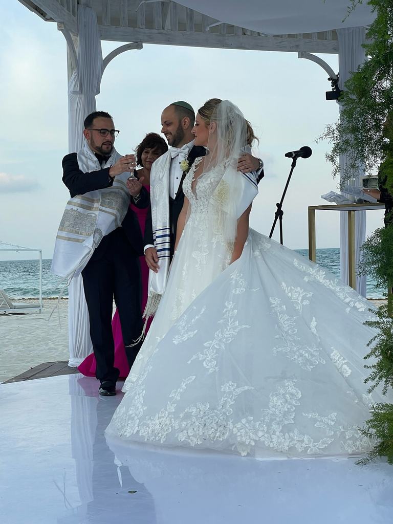 Todd Bronshtein holds the kiddush cup for a bride and groom during a beachside wedding ceremony