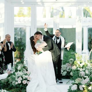 Newlyweds kiss beneath the chuppah as officiant Todd Bronshtein cheers