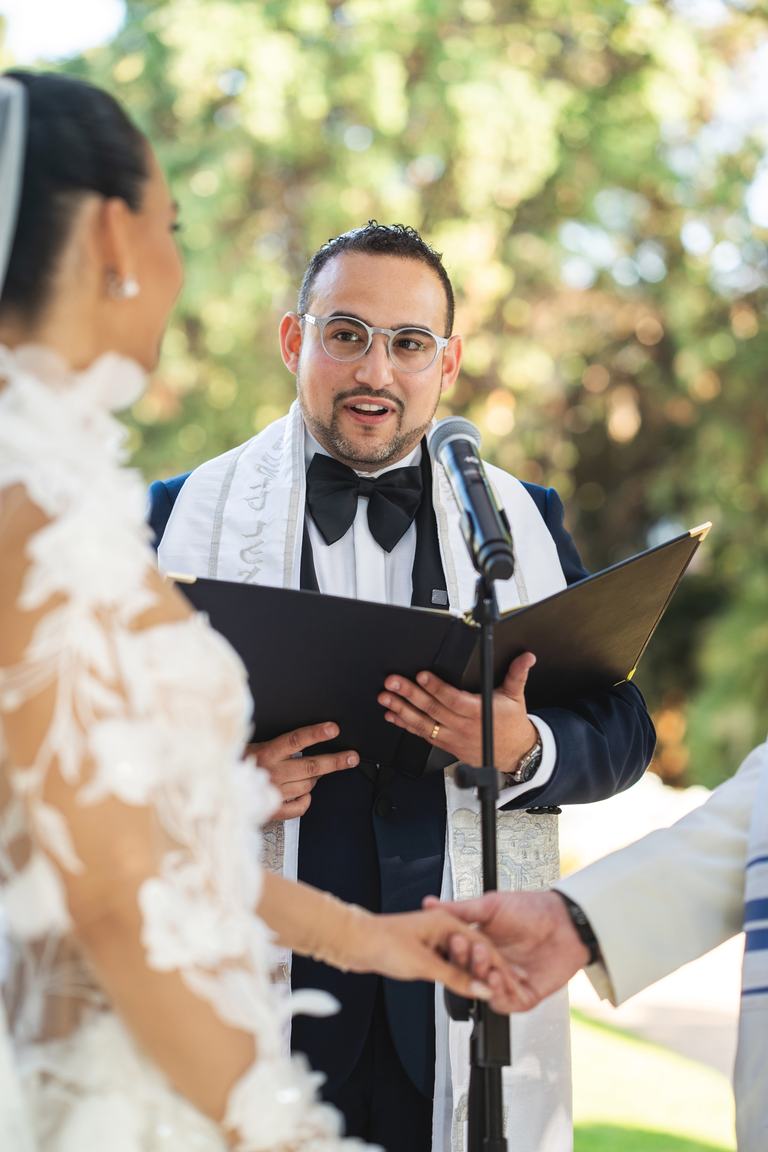 Todd Bronshtein leading a wedding ceremony as the couple holds hands